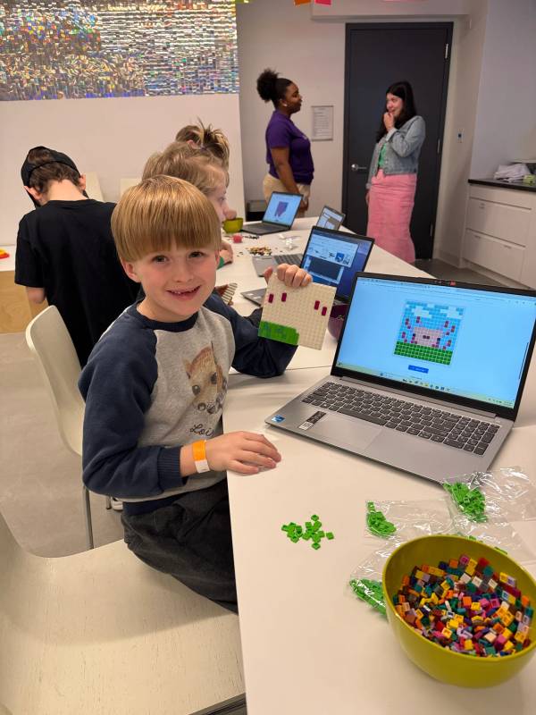 A camper holds up a pixel-art build made of small bricks