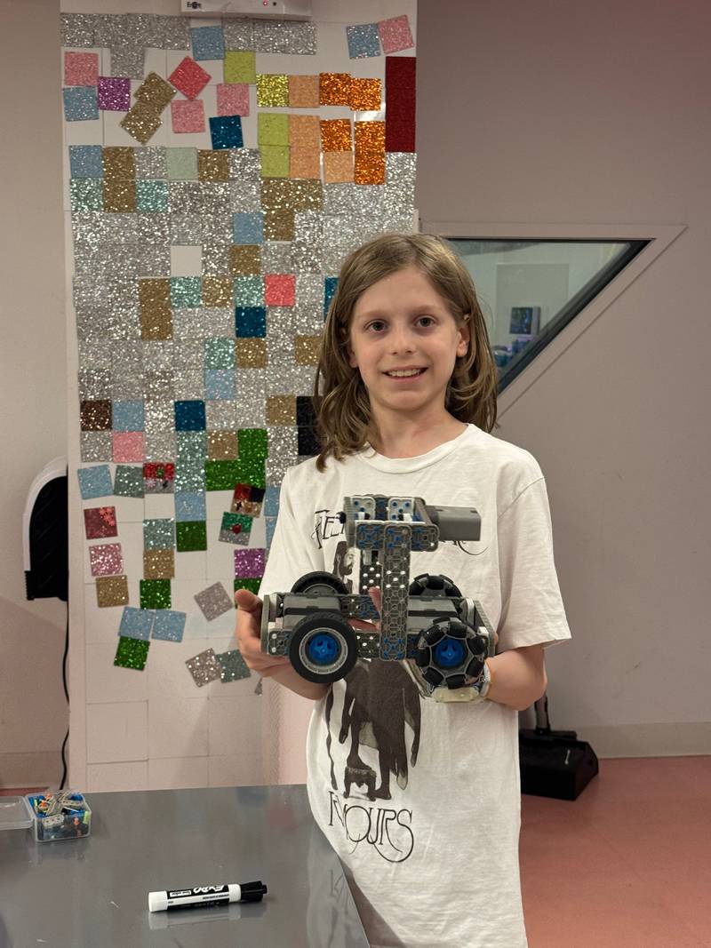 A girl holding up the robot she built in class at Genius Gems NYC