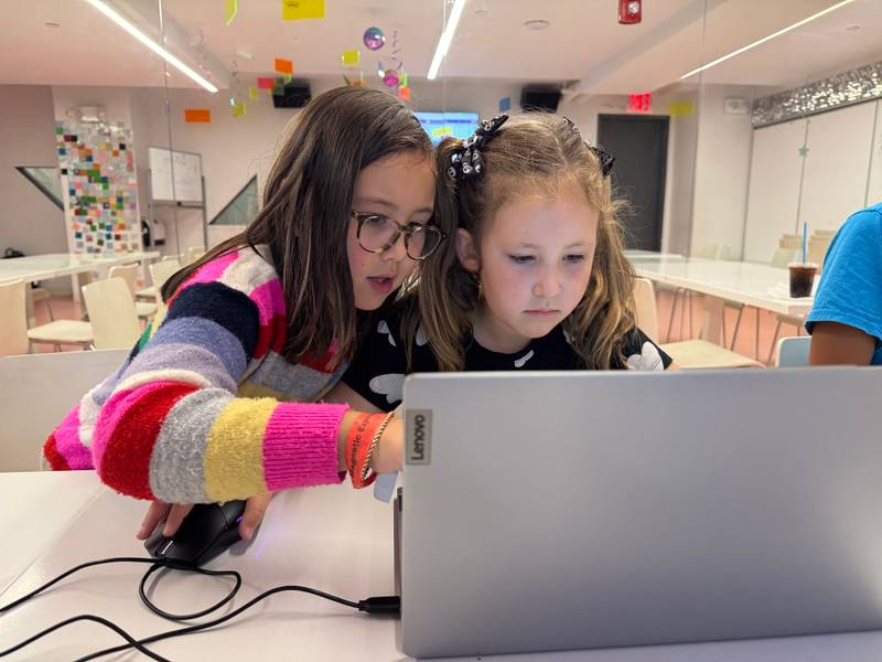 Two girls working through a coding lesson on a laptop at Genius Gems NYC