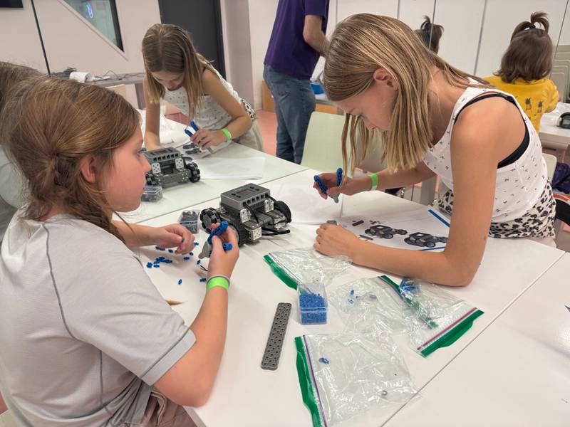 Two girls building robots from small blue pieces at Genius Gems NYC
