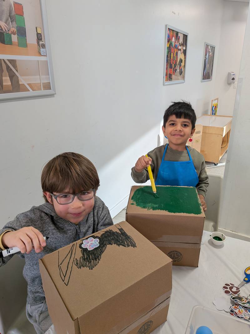 Two boys drawing and painting cardboard builds in a design class