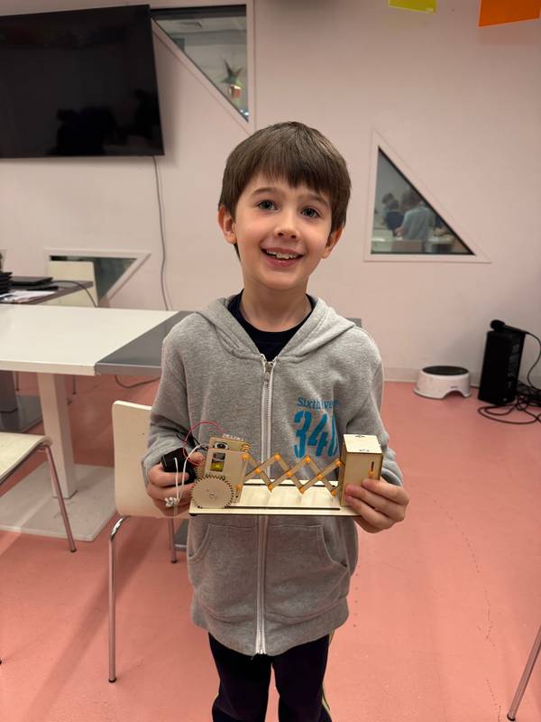 A camper shows off a handcrafted wooden robot with gears