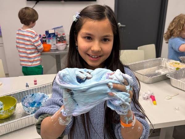 A camper holds up a large blob of blue and purple slime