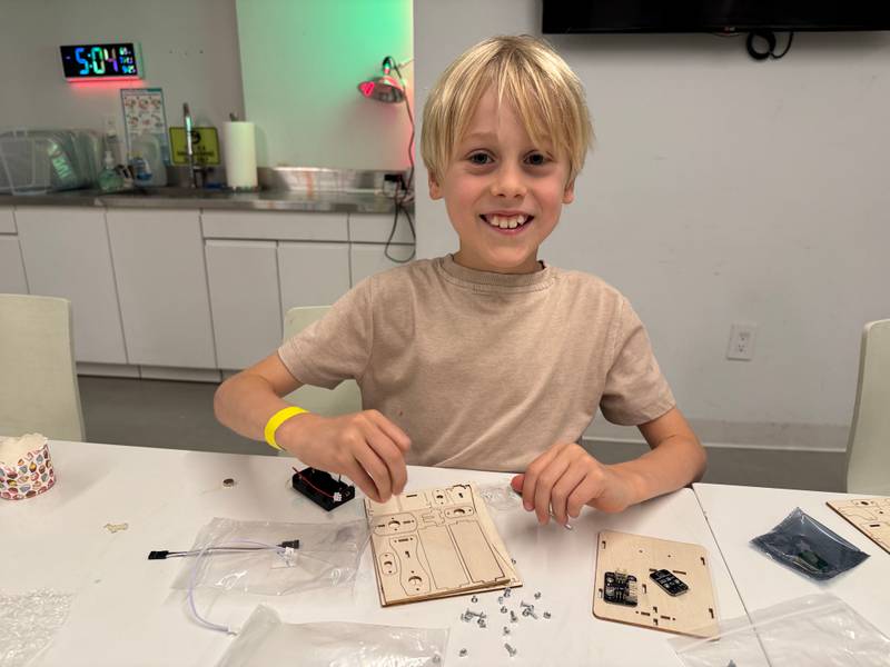 A boy assembling a wooden robot kit at Genius Gems NYC