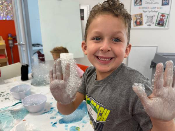 A camper shows off hands covered in iridescent soap bubbles