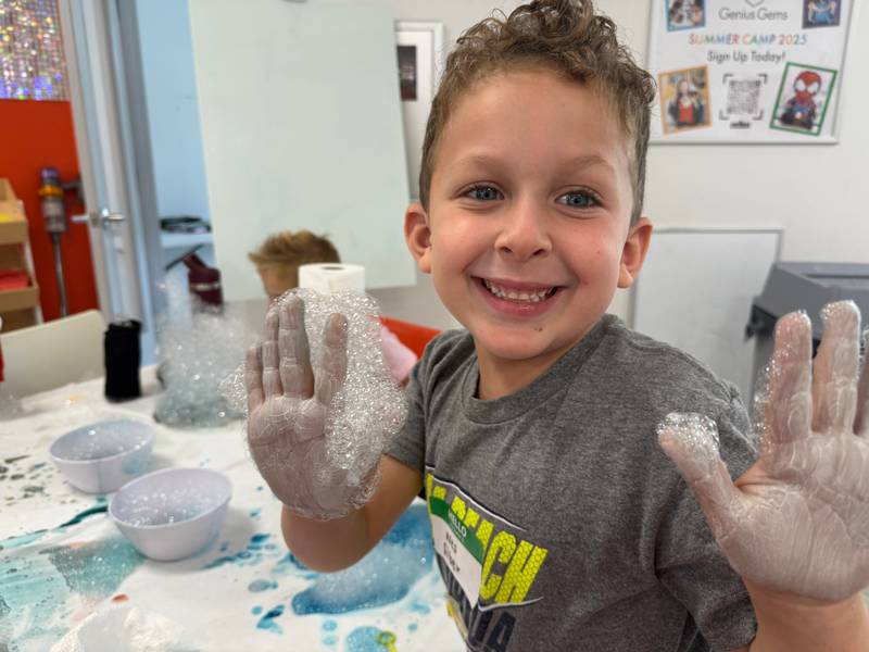 A boy showing off his hands covered in iridescent soap bubbles
