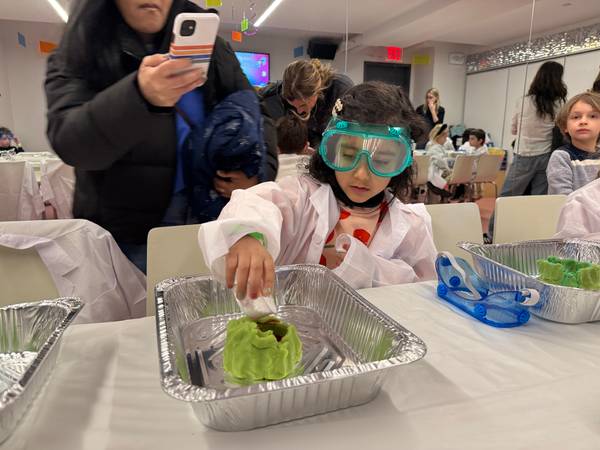 A camper in goggles and a lab coat sets off a volcano experiment