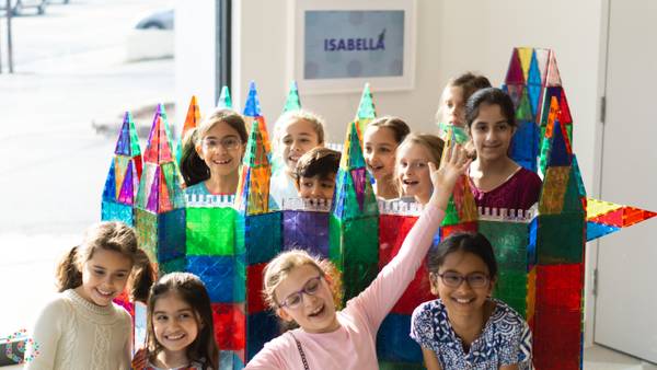 Four laughing kids in party hats behind a tile castle