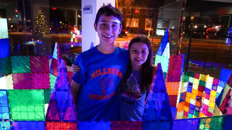 Two smiling kids behind a glowing magnetic-tile castle at Genius Gems Millburn