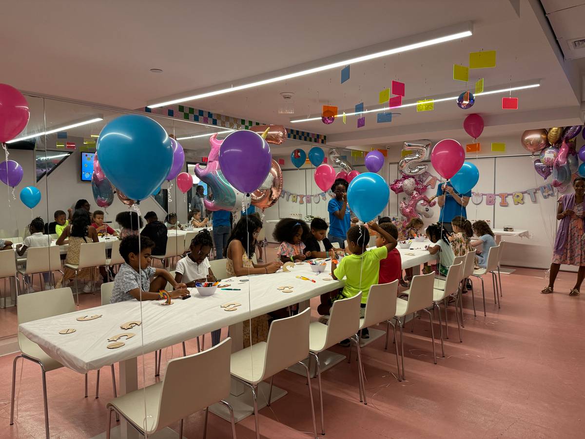 The Genius Gems NYC party room — a dozen kids at a long white table working on their project