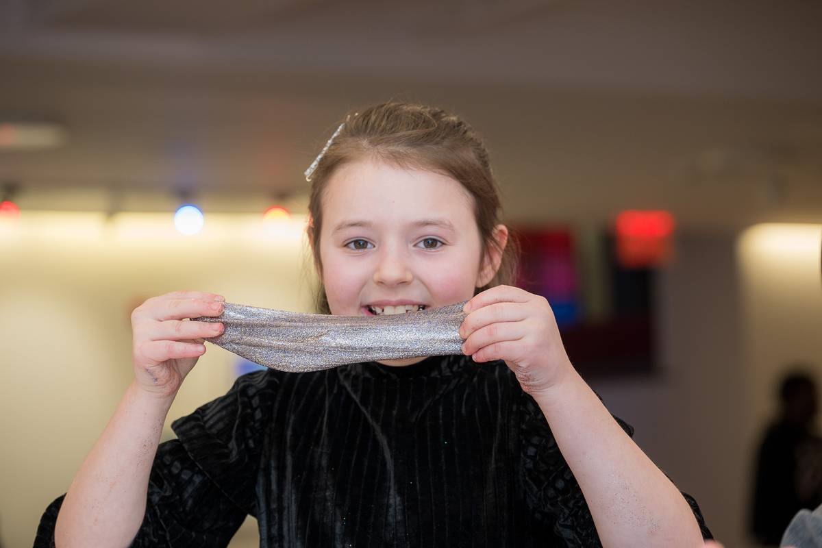 A party guest stretching the silver glitter slime she just made