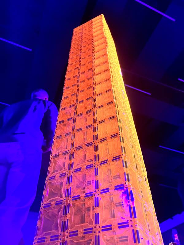 A towering magnetic tile skyscraper glowing orange under blacklight