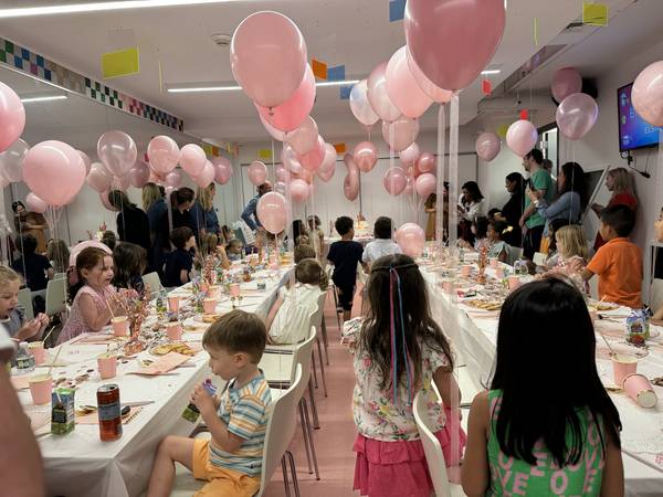 A decorated Genius Gems party room with pink balloons on every table