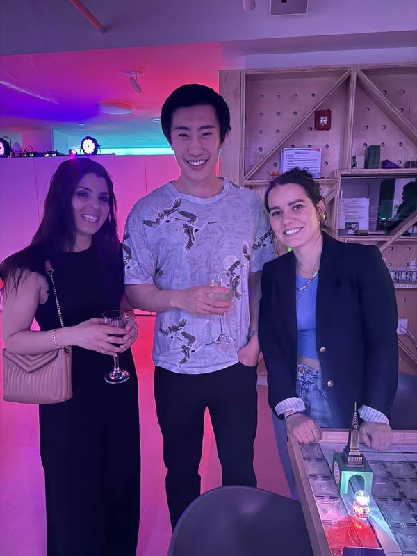 Three adults with wine glasses beside a magnetic tile build table