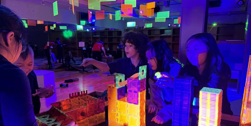 Kids building glowing magnetic-tile towers and a marble run at a Genius Gems Date Night