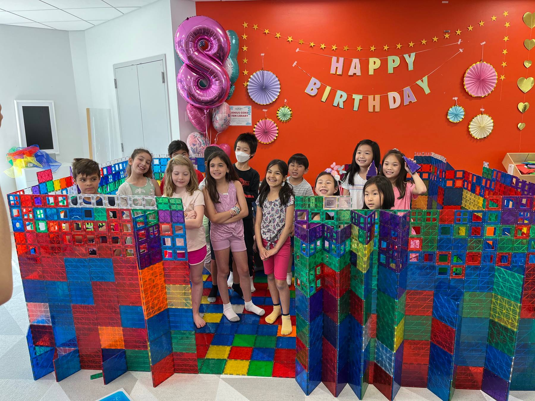 The Millburn party room — a dozen kids inside the magnetic-tile wall they built, under a Happy Birthday banner