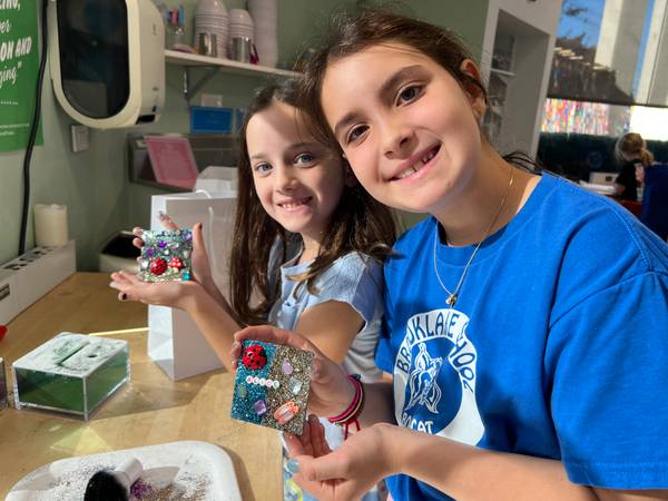 Two girls holding up the glitter tiles they designed