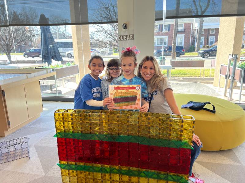 A mom and three girls with the giant magnetic tile hamburger they built for a challenge card at Genius Gems Millburn