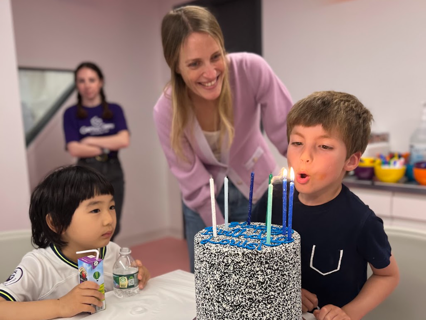 The birthday song — a boy blowing out the candles on a sprinkle cake at Genius Gems
