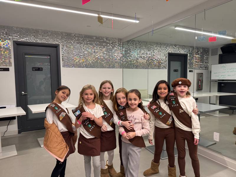 Seven Brownies in sashes smiling together at Genius Gems in Chelsea