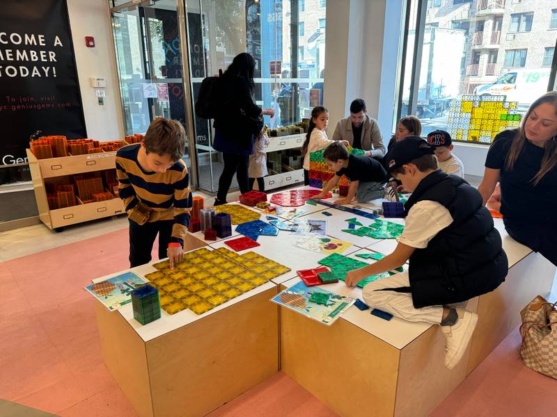 Kids and parents building with colourful magnetic tiles at the play tables at Genius Gems NYC